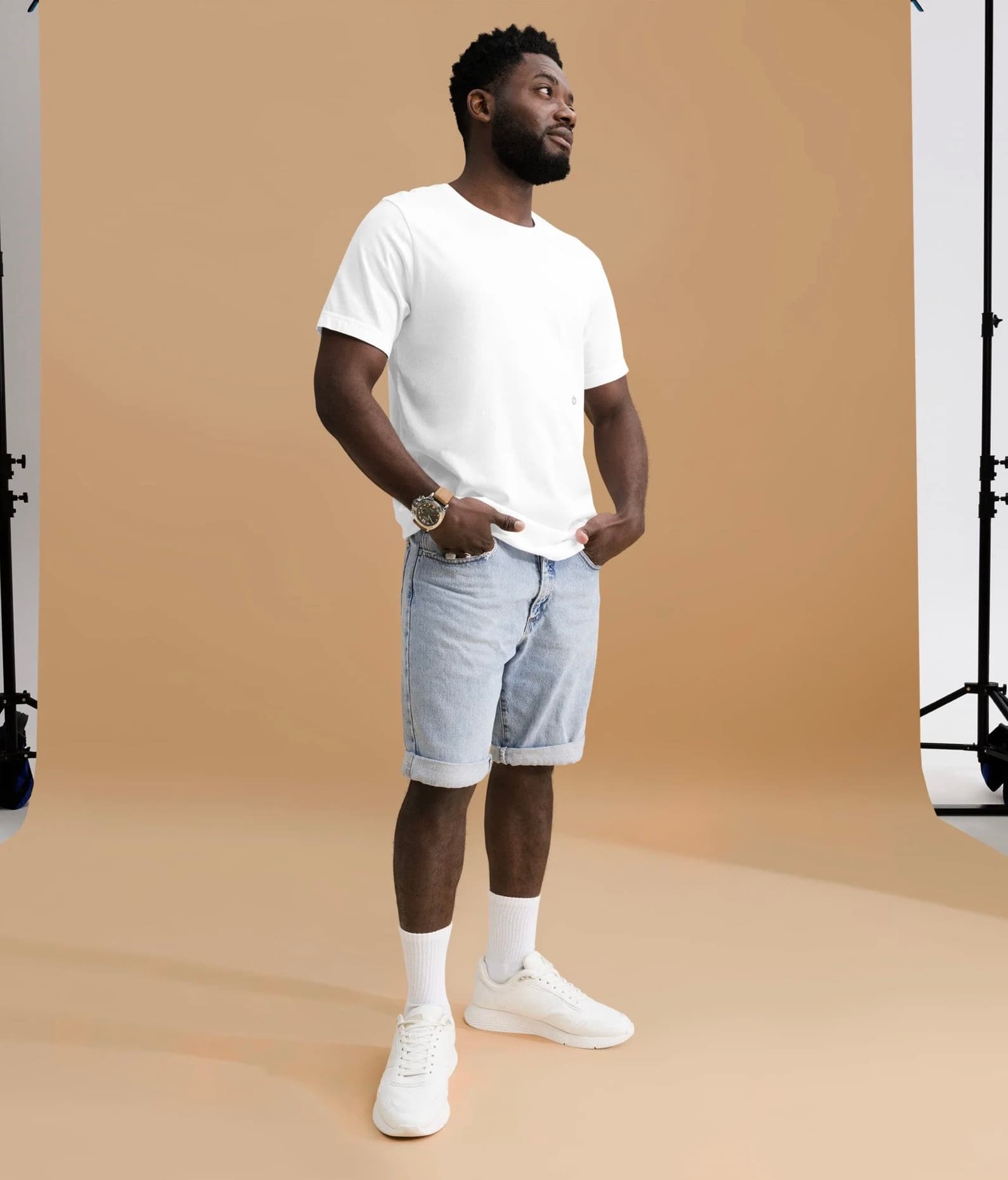 A man in the white Basic Garment Top and denim shorts in a photo studio.